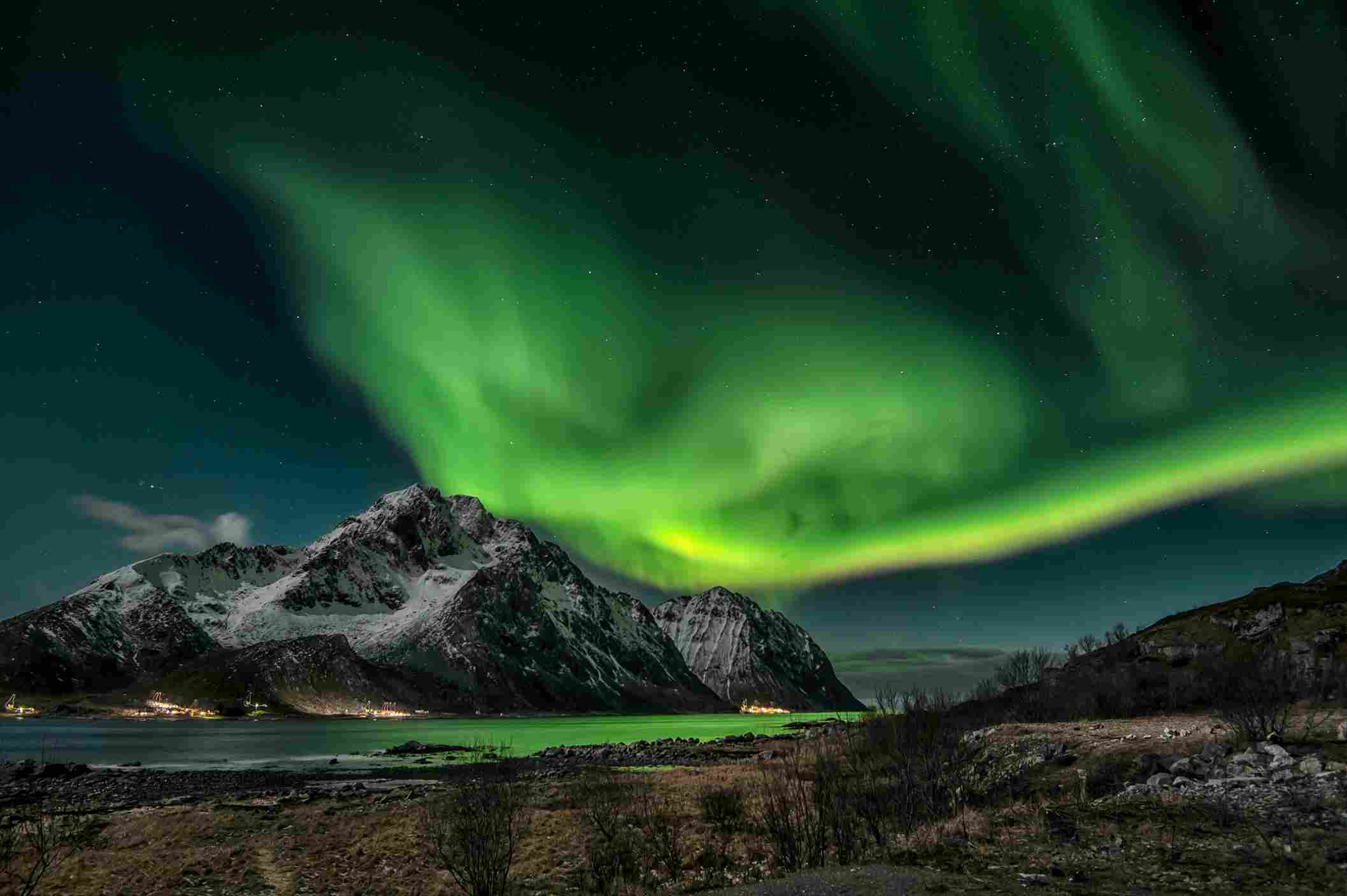 Green aurora borealis northern lights over snowy mountain lake Russia winter night