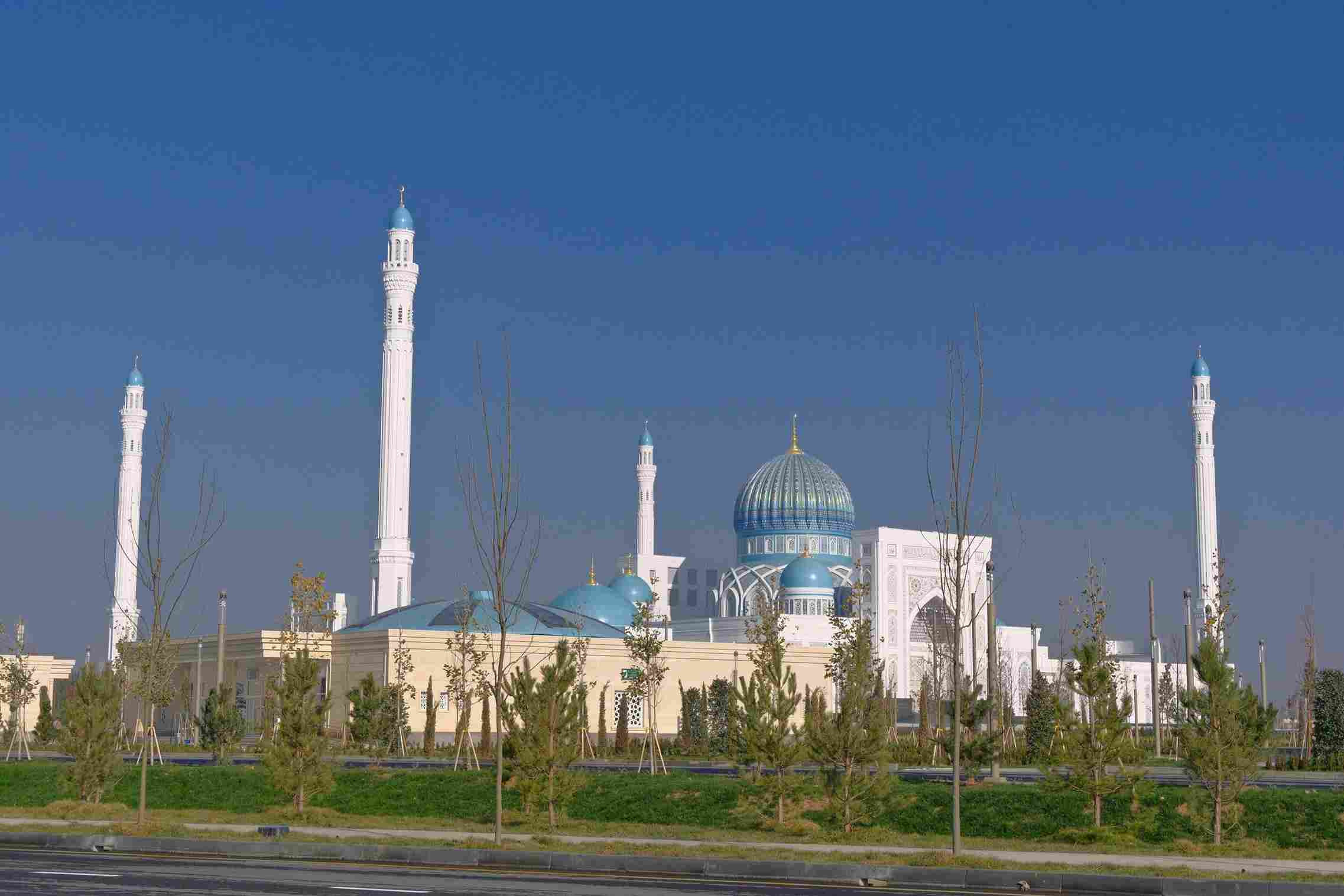 Grand white marble mosque with turquoise domes and tall minarets in Ashgabat, Turkmenistan, under a clear blue sky