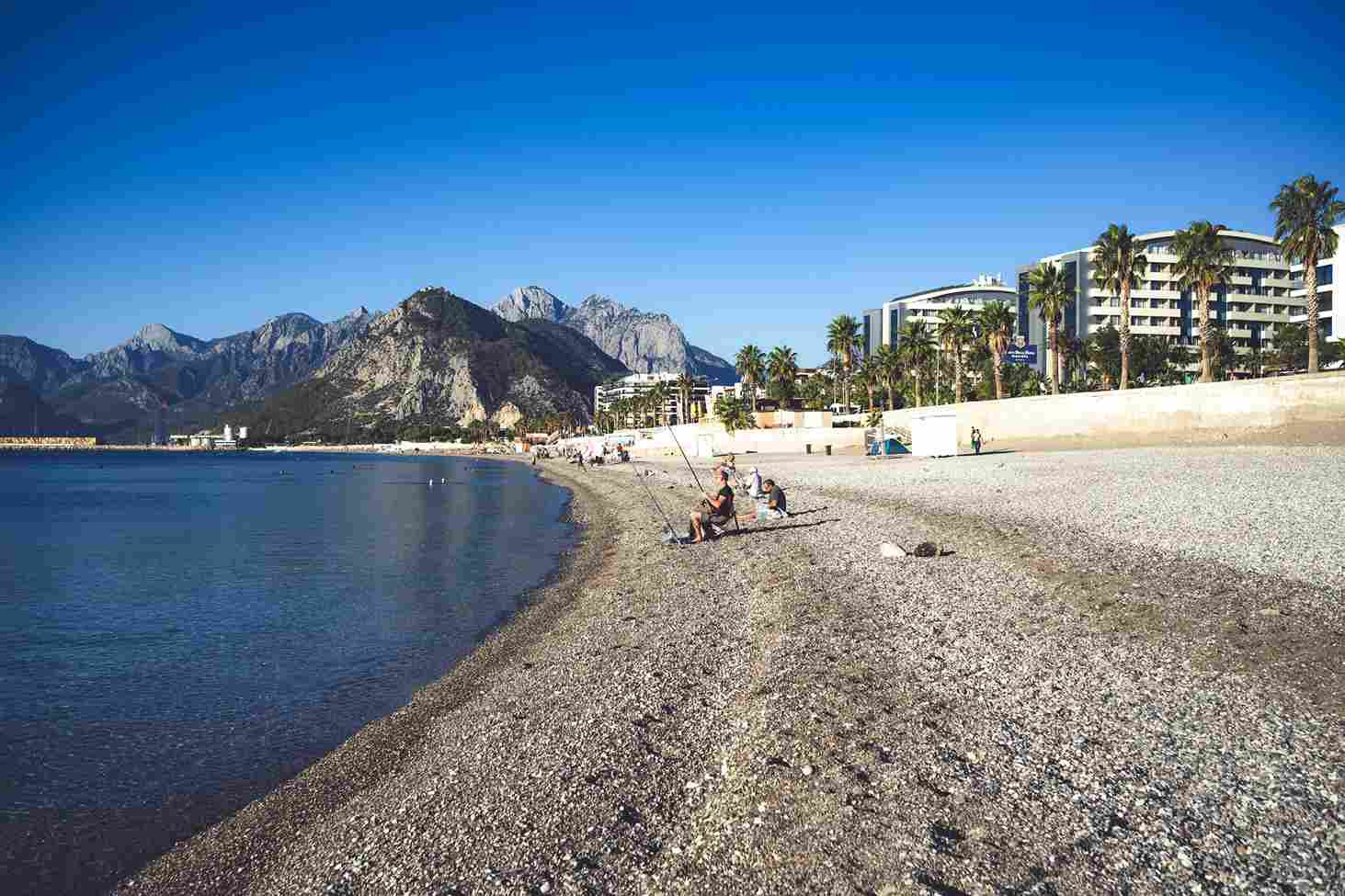 Gonio Beach Batumi pebble shore with fishermen, palm trees, mountains, and Black Sea coastline, Georgia